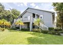 Gray condo building with exterior stairs, landscaping, and grassy yard at 11847 Skylake Pl # D, Tampa, FL 33617