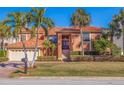 Two-story house with tile roof, attached garage, and manicured lawn at 207 8Th E St, Tierra Verde, FL 33715