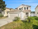Two-story house with beige exterior, attached garage, and landscaping at 32328 Fish Hook Loop, Wesley Chapel, FL 33545