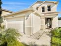 Two-story house with beige exterior, attached garage, and landscaping at 32328 Fish Hook Loop, Wesley Chapel, FL 33545