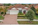 One-story house with a tile roof, two-car garage, and neatly trimmed hedges at 11910 Climbing Fern Ave, Riverview, FL 33579