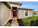 Inviting front entrance with a red door and neatly trimmed landscaping at 1215 Dustan Pl, Trinity, FL 34655
