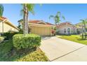 Tan house with a three car garage and manicured lawn at 14608 Mirasol Manor Ct, Tampa, FL 33626