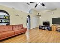 Living room with hardwood floors, a brown couch, and a vaulted ceiling at 30618 Birdhouse Dr, Wesley Chapel, FL 33545
