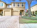 Tan two-story house with two-car garage, paver driveway, and American flag at 17523 Stinchar Dr # 17523, Land O Lakes, FL 34638