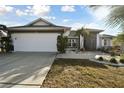 White and gray house with a two-car garage and well-manicured lawn at 326 Caloosa Woods Ln, Sun City Center, FL 33573
