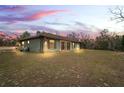 Green house exterior at dusk with landscape at 12404 Dolquieb Ln, Weeki Wachee, FL 34614