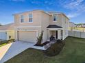 Two-story house with beige exterior, two-car garage, and landscaped front yard at 38296 Sonnet Landing Ave, Zephyrhills, FL 33540
