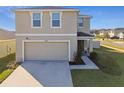 Two-story house with beige exterior, two-car garage, and front yard landscaping at 38296 Sonnet Landing Ave, Zephyrhills, FL 33540