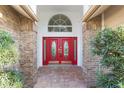Inviting entryway featuring a striking red double door with decorative glass and brick columns at 8701 Ballantrae Way, Tampa, FL 33647