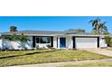 Newly renovated home with white brick exterior, gray roof, and a blue front door at 3946 Doral Dr, Tampa, FL 33634