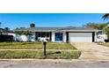 Newly renovated home with white brick exterior, gray roof, and a blue front door at 3946 Doral Dr, Tampa, FL 33634