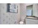 Stylish powder room with patterned wallpaper and granite vanity at 4318 Pullet Ct, Lakewood Ranch, FL 34211