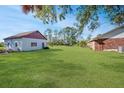 Large grassy backyard with detached garage and shaded seating area at 10813 Dixon Dr, Riverview, FL 33579