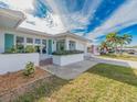 Front view of a white brick house with teal accents and lush landscaping at 14052 89Th Ave, Seminole, FL 33776
