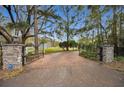 Stone pillars and wrought iron gates open to a brick driveway at 249 Dogwood Trce, Tarpon Springs, FL 34688