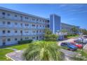 Condo building exterior showcasing light blue facade, parking, and landscaping at 5555 Gulf Blvd # 209, St Pete Beach, FL 33706