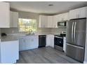 Modern kitchen featuring white cabinetry, stainless steel appliances, quartz countertops, and gray floors at 6666 Pinellas Point S Dr, St Petersburg, FL 33712