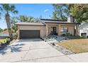 Lovely home with a dark garage door, stone accents, landscaping, and walkway leading to the front door at 1033 Jamaica Way, Tarpon Springs, FL 34689