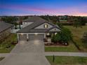 Two-story house with three car garage and landscaped yard at dusk at 12314 Bay Estuary Bnd, Riverview, FL 33579
