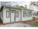 White stucco house with a green trim, sunroom, and nicely manicured lawn at 6699 78Th N Ave, Pinellas Park, FL 33781