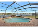 Screened-in pool with lake view and patio furniture at 7643 Vienna Ln, Port Richey, FL 34668
