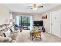 Living room with gray sectional, TV, and balcony access at 3141 Lake Pine Way # D2, Tarpon Springs, FL 34688