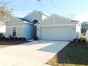 Single-story house with light blue exterior, two-car garage, and well-manicured lawn at 504 Magnolia Pointe Ct, Seffner, FL 33584