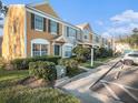 Row of townhomes showcasing yellow and gray siding, landscaping, and parking at 1241 Redondo Way, Wesley Chapel, FL 33543