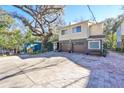 Tan two-story house with a brown double garage door and mature trees in front at 1745 E Mulberry Dr, Tampa, FL 33604