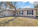 House exterior showcasing beige siding, black shutters, and a landscaped yard at 12575 Maleo Rd, Weeki Wachee, FL 34614