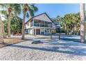Two-story house with screened porch, palm trees, and a gravel driveway at 3478 Gum Dr, Weeki Wachee, FL 34607