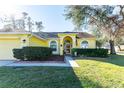 Charming yellow house with an arched entryway and well-maintained landscaping at 5215 New Brittany Ln, Zephyrhills, FL 33541