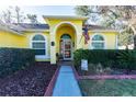 Welcoming yellow house with an arched entryway, landscaping, and walkway at 5215 New Brittany Ln, Zephyrhills, FL 33541