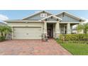 Charming home featuring a brick driveway, two-car garage, and decorative front porch at 6028 Milestone Dr, Apollo Beach, FL 33572