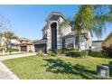 Two-story house with gray siding, dark garage door, and landscaping at 3030 Trinity Cottage Dr, Land O Lakes, FL 34638