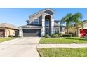 Two-story house with gray siding, dark garage door, and landscaping at 3030 Trinity Cottage Dr, Land O Lakes, FL 34638