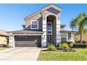 Two-story house with gray siding, dark garage door, and landscaping at 3030 Trinity Cottage Dr, Land O Lakes, FL 34638