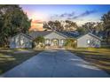 White house exterior at sunset, palm trees, and long driveway at 31445 Amberlea Rd, Dade City, FL 33523