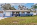 Ranch-style home with gray and blue exterior, landscaping, and a white garage door at 3282 Honeysuckle Rd, Largo, FL 33770