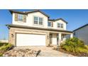 Two-story house with stone and light-colored siding, a two-car garage, and landscaping at 7815 Bronze Oak Dr, Wesley Chapel, FL 33545