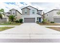 Two-story house with gray siding, gray garage door and blue front door at 16719 Delia St, Wimauma, FL 33598