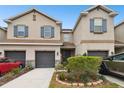 Tan three-story townhouse with gray garage doors and landscaping at 8126 Muddy Pines Pl, Tampa, FL 33635