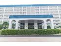Condo building entrance with arched entryway and lush landscaping at 7 Elgin Pl # 812, Dunedin, FL 34698