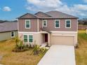 Two-story house with brown siding, beige garage door, and landscaping at 11307 Linden Depot Rd, San Antonio, FL 33576