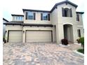 Tan two-story house with a three-car garage and landscaping at 12854 Boggy Creek Dr, Riverview, FL 33579
