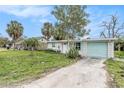 Front view of a ranch home with light brick, teal garage door, and palm trees at 6702 Sandra Dr, Port Richey, FL 34668