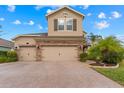 Two-story house with a stone facade, three-car garage, and a brick driveway at 1737 Fox Grape Loop, Lutz, FL 33558
