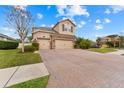 Two-story house with a stone facade, three-car garage, and a brick driveway at 1737 Fox Grape Loop, Lutz, FL 33558
