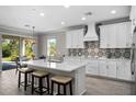 Modern kitchen with white cabinets, quartz countertops, and decorative backsplash at 19891 Bridgetown Loop, Venice, FL 34293